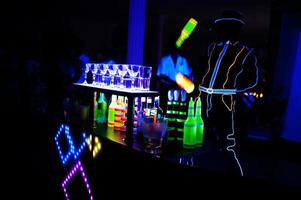 professioneel barman en LED licht show. silhouet van modern barman beven drinken Bij nacht cocktail bar. foto