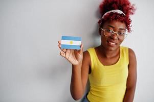 Afrikaanse Amerikaans vrouw met afro haar, slijtage geel singlet en bril, houden Argentinië vlag geïsoleerd Aan wit achtergrond. foto