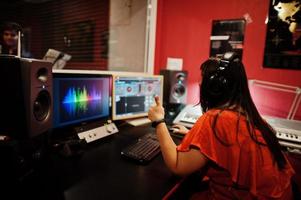 jong Aziatisch zanger Mens met microfoon opname lied in Vermelding muziek- studio met geluid producent. foto