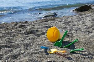 kinderen speelgoed Aan de kust, een emmer, een lepel, een hark liggen Aan een rotsachtig strand. kind veiligheid concept. foto