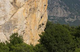 een puur muur van rood-grijs kleur Aan een rots in de bergen, de structuur van natuurlijk steen. actief sport. achtergrond foto