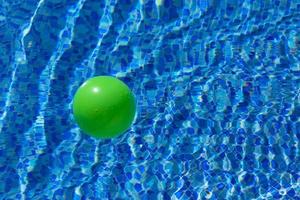 ronde groen bal Aan de oppervlakte van de water in een zwembad met blauw water en golven. de concept van kinderen veiligheid in de buurt de water. foto