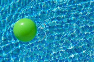 ronde groen bal Aan de oppervlakte van de water in een zwembad met blauw water en golven. de concept van kinderen veiligheid in de buurt de water. foto
