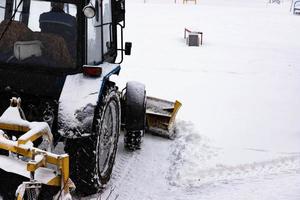 de trekker wist de weg van sneeuw in winter gedurende een sneeuwval. foto