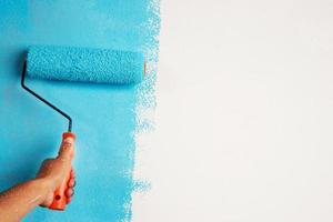 rol borstel schilderen, arbeider schilderij Aan oppervlakte muur schilderij appartement, renoveren met blauw kleur verf. vertrekken leeg kopiëren ruimte wit naar schrijven beschrijvend tekst Daarnaast. foto