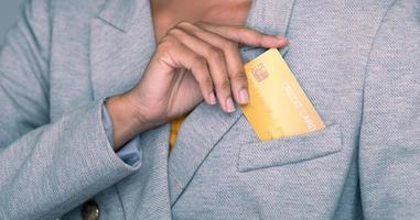 bedrijf vrouw houden goud credit kaart en boodschappen doen online van zak- brazer pak jasje wanneer inkoop. technologie helpen persoon boodschappen doen Bij huis in e-commerce op te slaan Aan mobiel telefoon of laptop foto