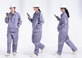 vol lengte Jaren 20 jong mengen ras ingenieur elektricien vrouw, gebruik makend van internet cel telefoon, slijtage grijs uniform. aannemer vrouw voelt glimlach gelukkig over- wit achtergrond geïsoleerd foto