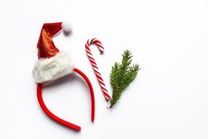 haar- band met de kerstman hoed, snoep riet en Spar boom Afdeling Aan wit achtergrond met kopiëren ruimte. feestelijk Kerstmis groet kaart. nieuw jaar oncept foto