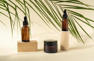 amber kunstmatig flessen met pipet Aan houten meetkundig voetstuk podia, Product verpakking met natuurlijk palm bladeren, anti veroudering serum met peptiden, schoonheidsmiddelen model, spa concept. foto