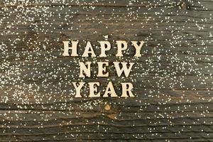 gelukkig nieuw jaar 2021 viering. houten tekst Aan houten achtergrond met verspreide gouden confetti. vlak leggen. foto