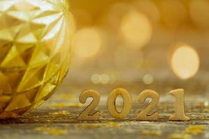 2021 houten getallen Aan bokeh achtergrond in gouden kleuren. feestelijk groet kaart vanaf nieuw jaar met kopiëren ruimte. foto