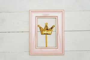 roze fotolijstje met gouden pailletten kroon Aan wit houten achtergrondkleur. minimaal vlak leggen met kopiëren ruimte. foto