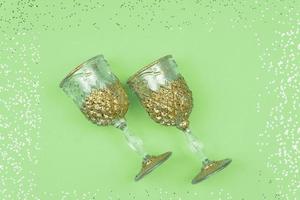twee leeg Champagne bril Aan groen sprankelend achtergrond. feestelijk groet kaart met confetti foto
