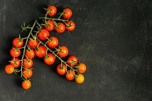 top visie van vers rijp kers tomaten Aan zwart achtergrond met kopiëren ruimte. ingrediënt voor middellandse Zee keuken. foto