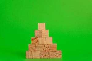 piramide bouw gemaakt van houten kubussen Aan groen achtergrond met kopiëren ruimte. mockup samenstelling voor ontwerp foto