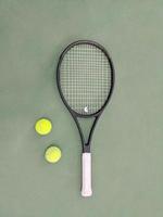 top visie van tennis racket en twee ballen Aan de groen klei tennis rechtbank foto