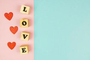 rood harten en houten kubussen met tekst liefde Aan dubbele blauw en roze achtergrond. creatief vlak leggen met kopiëren ruimte. feestelijk groet kaart voor st valentijnsdag dag. foto
