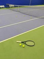 dichtbij omhoog visie van tennis racket en twee ballen Aan de groen klei tennis rechtbank foto