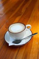 een kop van koffie latte Aan hout tafel foto