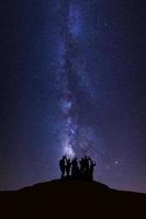 landschap met melkachtig manier, nacht lucht met sterren en silhouet van gelukkig mensen staand Aan hoog moutain foto