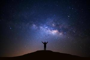 landschap met melkachtig manier, nacht lucht met sterren en silhouet van Mens staand Aan hoog moutain foto