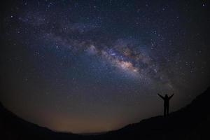 landschap met melkachtig manier, nacht lucht met sterren en silhouet van gelukkig mensen staand Aan berg, lang blootstelling fotograaf, met korrel. foto