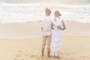 gelukkig jong paar vervelend wit jurk Aan de strand Aan vakantie, reis, romantisch, bruiloft concept foto