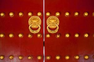 Chinese poort rood deuren met gouden draak hoofden kloppers foto