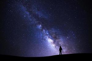 landschap met melkachtig manier heelal, sterrenhemel nacht lucht met sterren en silhouet van een staand Mens Aan hoog berg. foto