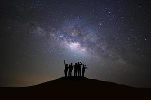 landschap met melkachtig manier heelal, sterrenhemel nacht lucht met sterren en silhouet van mensen staand gelukkig Mens Aan hoog berg. foto