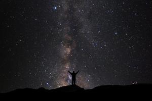 landschap met melkachtig manier, nacht lucht met sterren en silhouet van Mens staand Aan hoog moutain foto