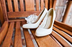 crème Trouwschoenen van bruid op houten stoel foto