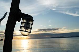 silhouet van retro straatlantaarn, lamp hangende Aan houten elektrisch pool. wijnoogst pijler met lamp. Doorzichtig leeg blauw lucht achtergrond, kopiëren ruimte. oud lantaarn foto