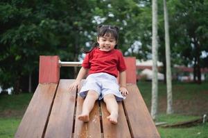 schattig aziatisch meisjesspel op school of kleuterschool of speelplaats. gezonde zomeractiviteit voor kinderen. klein Aziatisch meisje buiten klimmen op speelplaats. kind spelen op buitenspeeltuin. foto