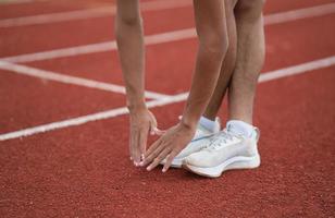 atleten sport Mens loper vervelend wit sportkleding naar uitrekken en warm omhoog voordat beoefenen Aan een rennen bijhouden Bij een stadion. loper sport concept. foto