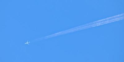 snel vliegtuig en rokerig vlucht spoor Aan blauw lucht foto