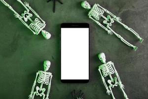 vier skeletten zijn aan het liegen in de buurt de smartphone Aan een donker achtergrond. foto