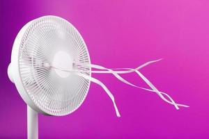 de elektrisch ventilator is wit met roze linten fladderend in de wind Aan een roze achtergrond. foto