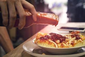 gieten tomaat saus uit van glas flessen Aan een pizza foto