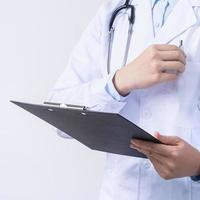 dokter met stethoscoop in wit jas Holding klembord, schrijven medisch Vermelding diagnose, geïsoleerd Aan wit achtergrond, dichtbij omhoog, bijgesneden visie. foto