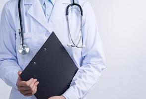 dokter met stethoscoop in wit jas Holding klembord, schrijven medisch Vermelding diagnose, geïsoleerd Aan wit achtergrond, dichtbij omhoog, bijgesneden visie. foto