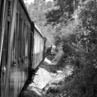 speelgoed- trein in beweging Aan berg helling, mooi visie, een kant berg, een kant vallei in beweging Aan spoorweg naar de heuvel, tussen groen natuurlijk bos.speelgoed trein van kalka naar shimla in india-zwart en wit foto