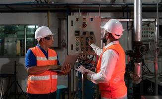 ingenieur van een mechanisch fabriek inspecteren en uitleggen de onderhoud van de controle paneel naar de monteur foto