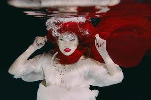 vrouw in rood hoed en rood sjaal onderwater- foto