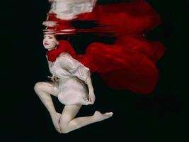 vrouw in rood hoed en rood sjaal onderwater- foto