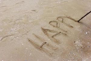 woord gelukkig geschreven Aan strand zand foto