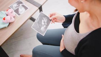 gelukkig Aziatisch zwanger vrouw aan het kijken echografie beeld Aan bank. foto