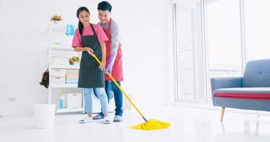 man helpen vrouw schoonmaak hun kamer. gelukkig Aziatisch paar uitgeven tijd samen Bij huis. foto