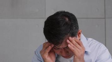 Aziatisch oud Mens met migraine hoofdpijn. Mens voelen benadrukt en bezorgd over Gezondheid problemen. foto