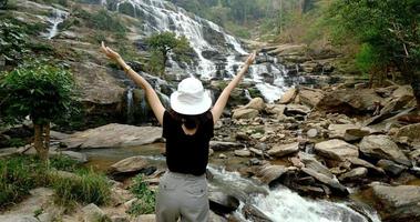 gelukkig vrouw staand en aan het kijken vloeiende waterval. foto